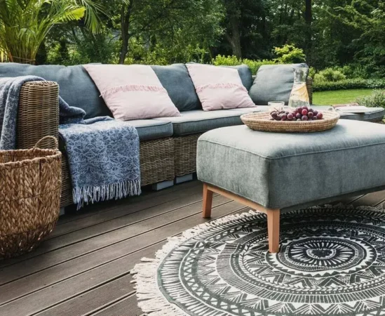 Outdoor patio with sofa, ottoman, and decorative rug.